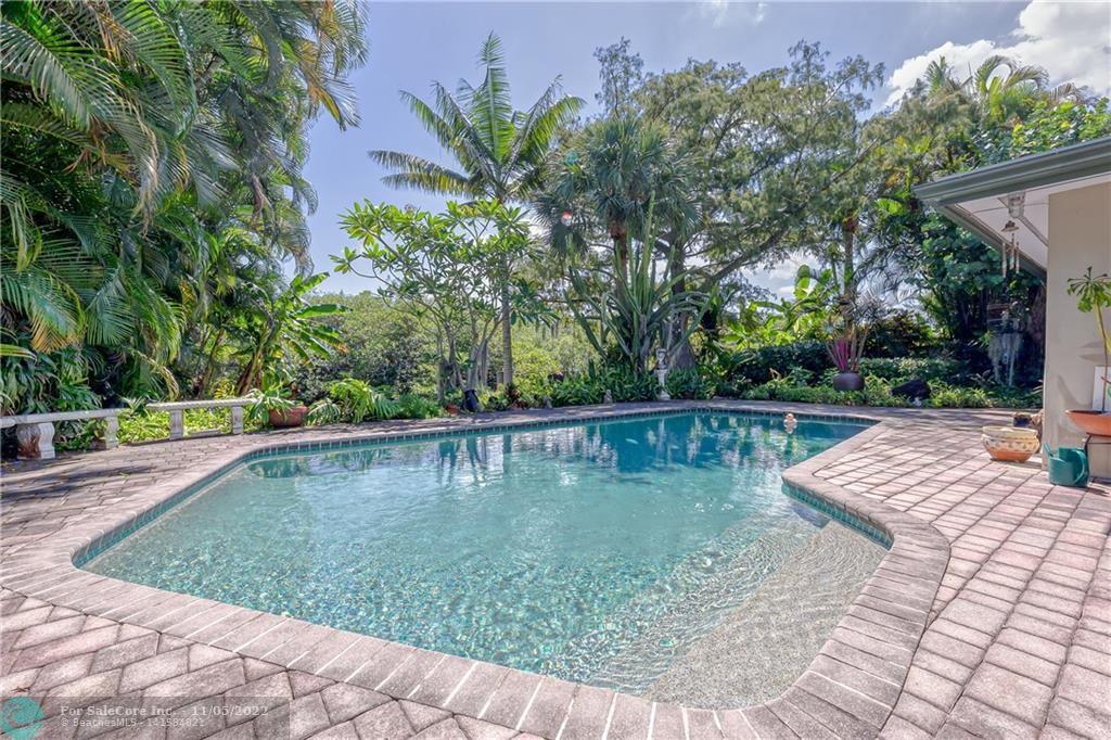 Hard to find a PRIVATE WATERFRONT POOL YARD --  This large lot (8,497sf) sits on the North Fork of the Middle River, across from a mangrove island growing in the middle of the waterway!  Lush tropical landscaping and specimen palms populate the grounds.  Home has 3 bedrooms, 2 bathrooms plus plumbing in the carport storage / laundry area for a 3rd cabana bathroom.  All impact windows and doors.  Interior was gutted and renovated in 2011, retro Kitchen cute. This house is eligible for Renovation Financing to create your new kitchen! Shingle and flat roofs new in 2019 by Tiger Team.  Seawall approximately 77' with a 20'  deck / dock -- great area for kayaking / water sports, entertaining and viewing the wildlife.  House protected under termit