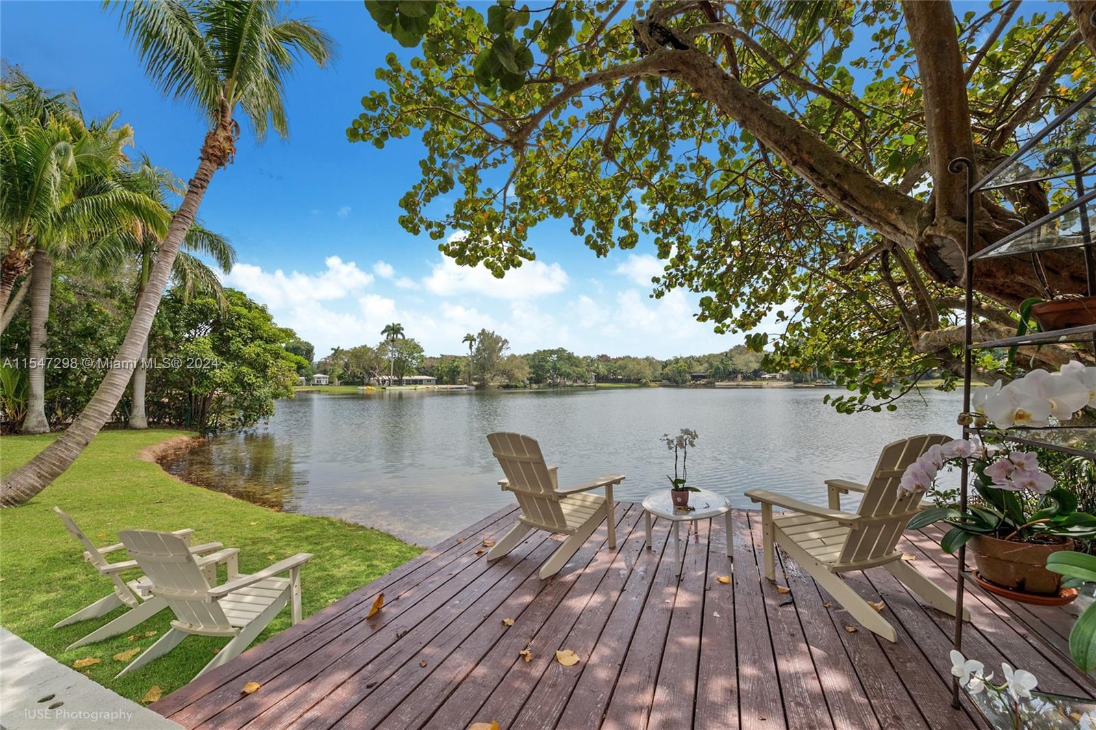 Privacy gates open to a deep lake-front acre and private oasis in South Gables, minutes from top sch