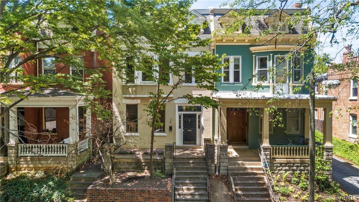 Nestled on the most charming side street in the historic fan neighborhood, this stunning Circa 1911 Rowhome is just a short walk to local Fan favorites including Sidewalk Cafe, Shyndigz, Lamplighter Coffee & many more. Relax outside enjoying the sights and sounds of RVA on the full brick & concrete front porch with stone planters and raised flower garden. Inside, fall in love with the original heart pine floors, exposed brick detail, numerous brick fireplaces, & spacious floor plan that includes a formal living & dining room, family room, and bright & open kitchen with bar seating and access to the adorable back yard with deck & privacy fence. Upstairs you'll find a huge owner's suite with expansive cathedral ceilings, exclusive primary full bath, exposed brick fireplace & direct access to the second floor "flex" room with built-in shelving and brick fireplace - perfect for your next home office or media room. Down the hall features two more spacious bedrooms with plenty of closet space, hardwood floors, and a second full bath. And if you decide to take this historic home to the next level, 14 N Rowland conveys with APPROVED building permits & plans to craft your urban dream home!!